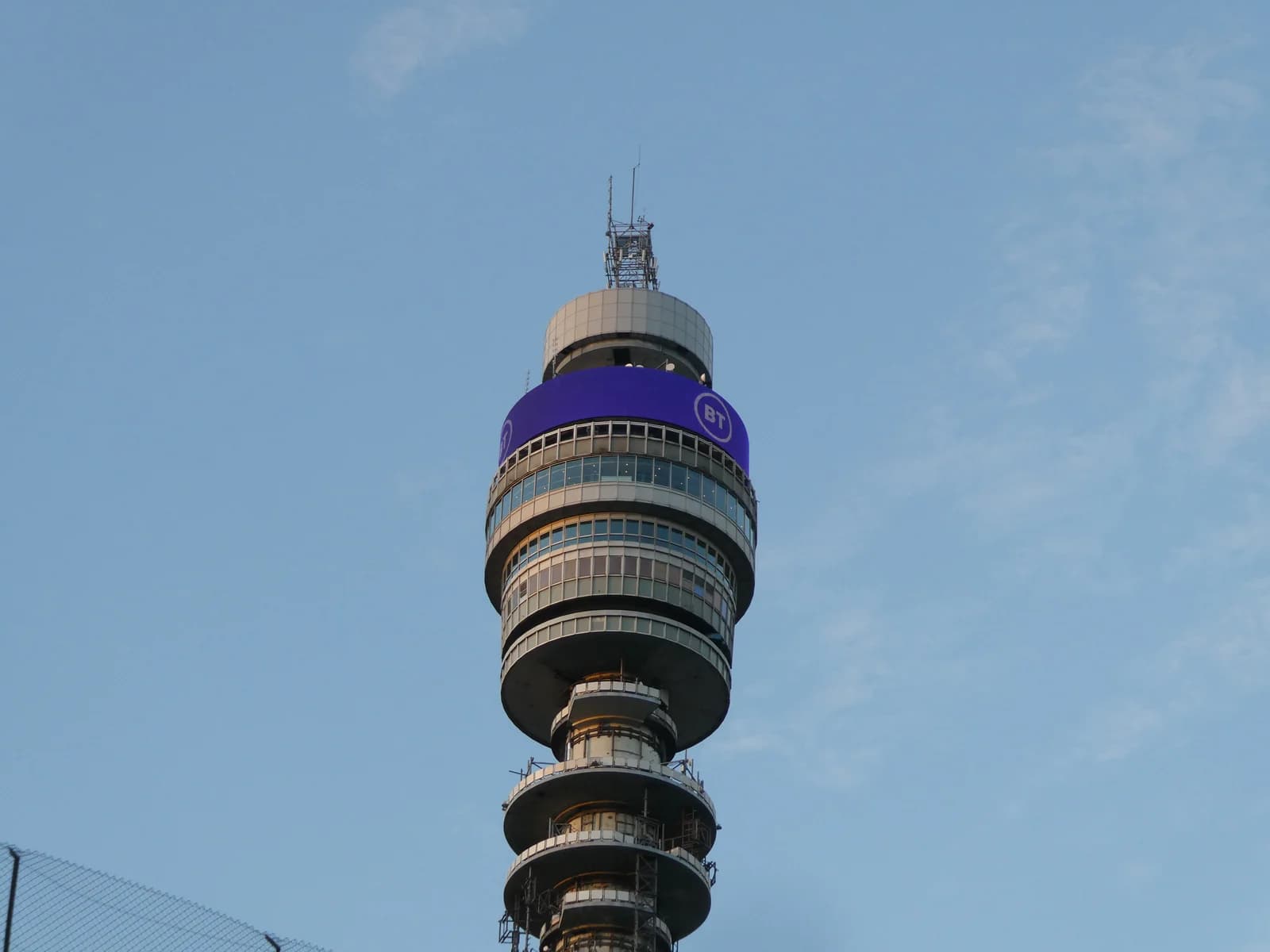 BT Tower, a telecommunications tower, against a light blue sky at dusk.