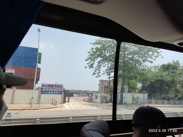 Shipping containers stacked at Zhongshan Ferry Port, seen from inside a bus.