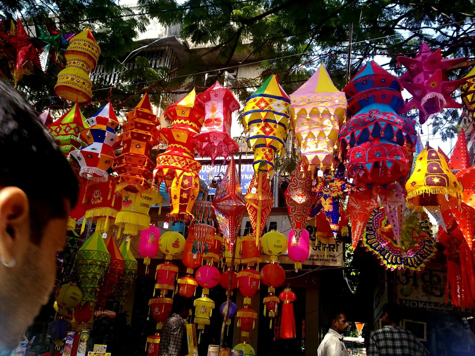 People shopping for colorful lanterns and decorations at a market stall in India.