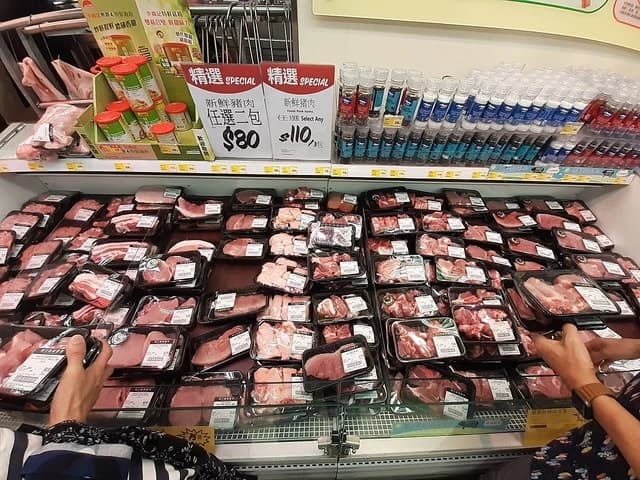 Packaged fresh pork on display in a refrigerated section of a Wellcome Supermarket.