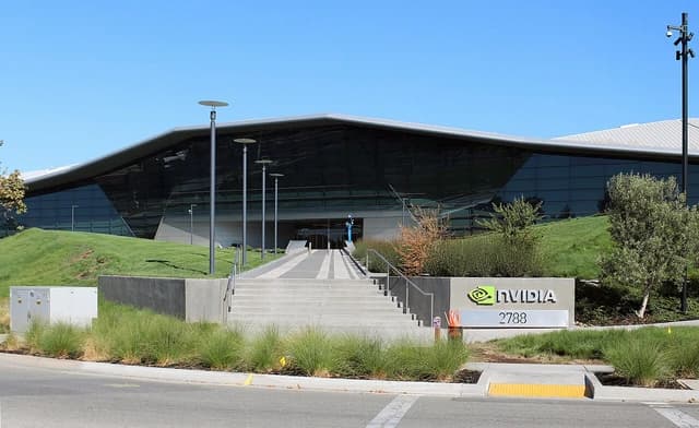 NVIDIA Headquarters building with glass facade and landscaped grounds under a clear blue sky.