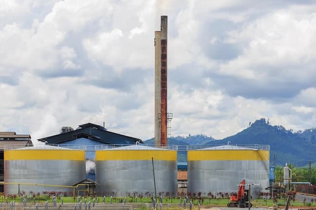Palm oil mill industrial site with large yellow and grey storage tanks.