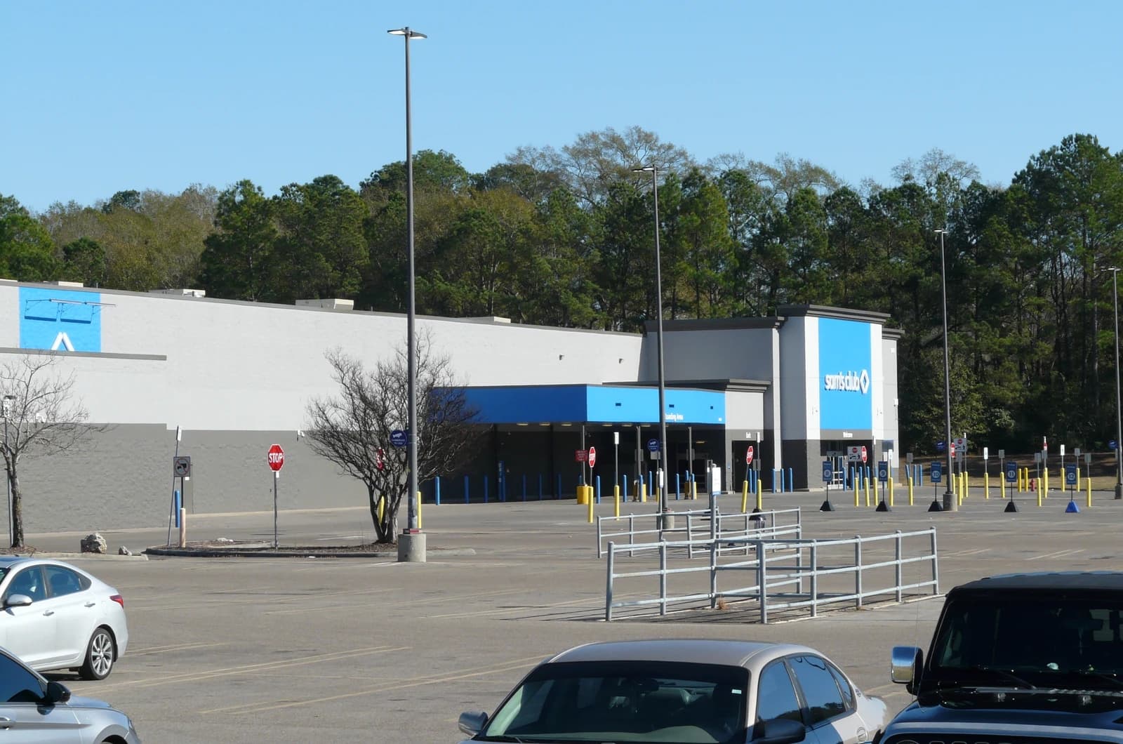 Exterior of a Sam's Club store with a large parking lot and some parked cars.