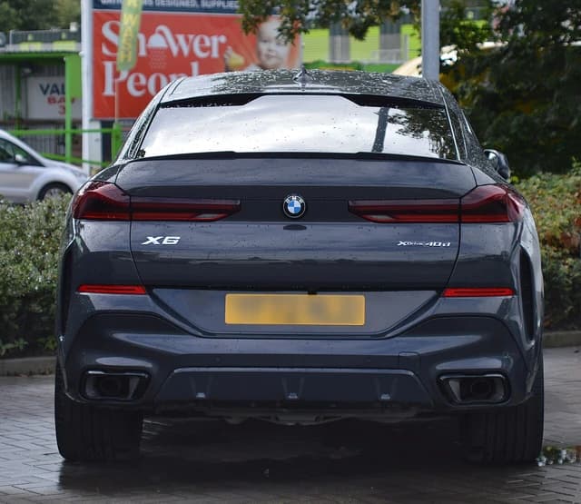 Rear view of a dark grey BMW X6 xDrive 40d parked on a paved surface.