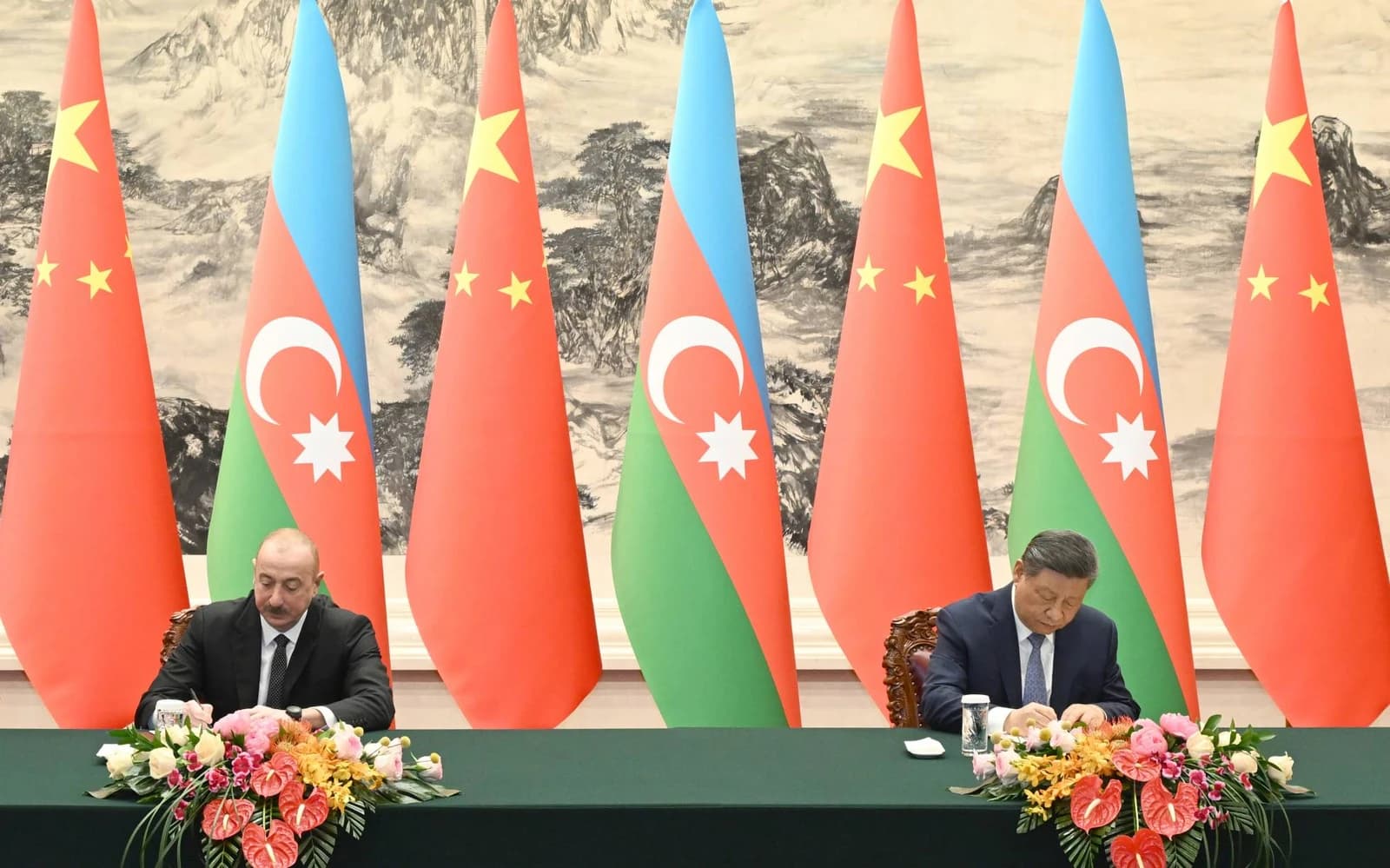 Chinese President Xi Jinping and Azerbaijani President Ilham Aliyev signing documents at a table.
