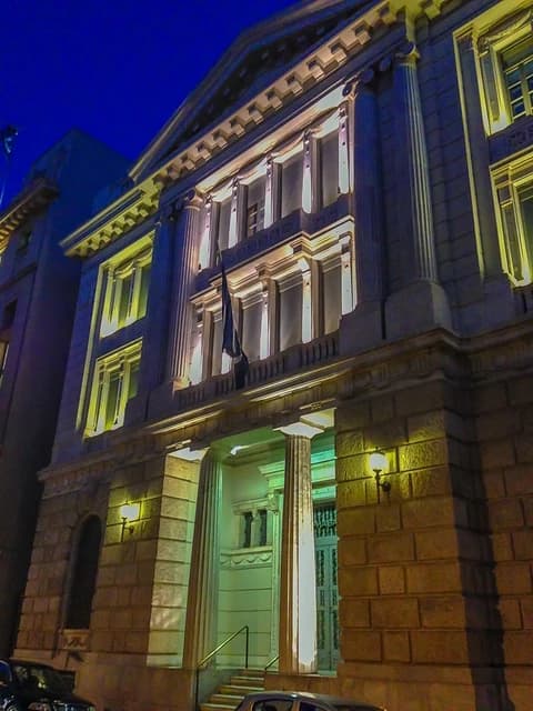 Headquarters of Alpha Bank in Athens at night, viewed from street level.