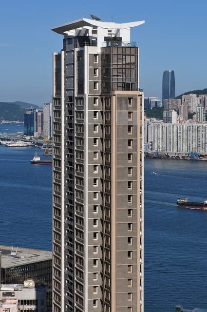 A modern tall residential building stands above the waters of Victoria Harbour in Hong Kong.