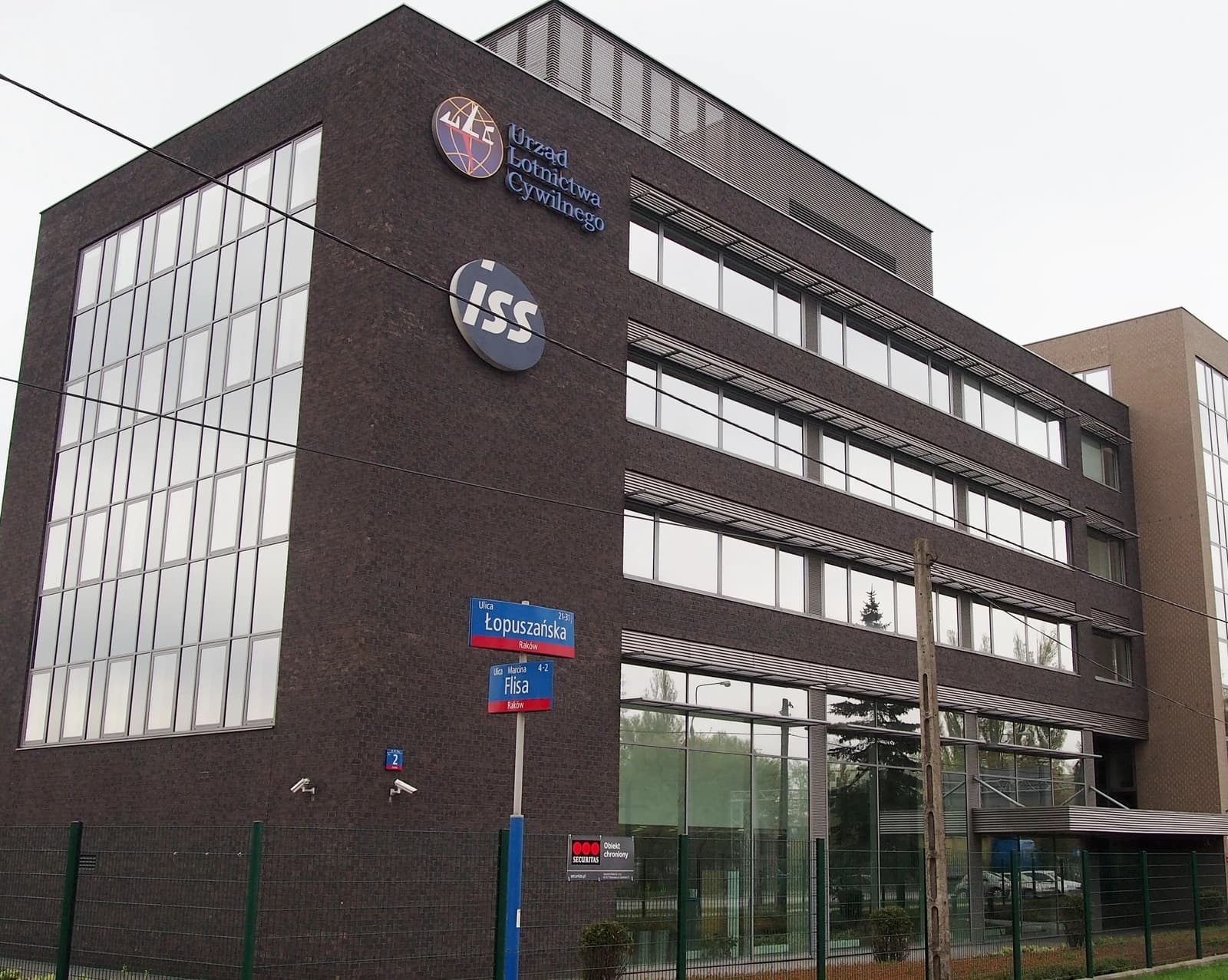 Exterior view of the Polish Civil Aviation Authority building with street signs in foreground.