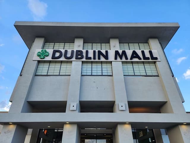 Exterior facade of Dublin Mall building with large black lettering and a green logo.