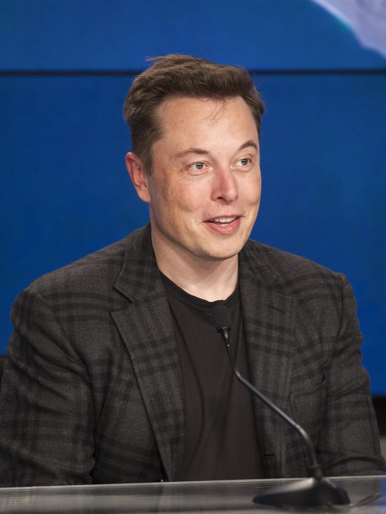 Elon Musk, CEO of SpaceX, speaking into a microphone at a press conference.