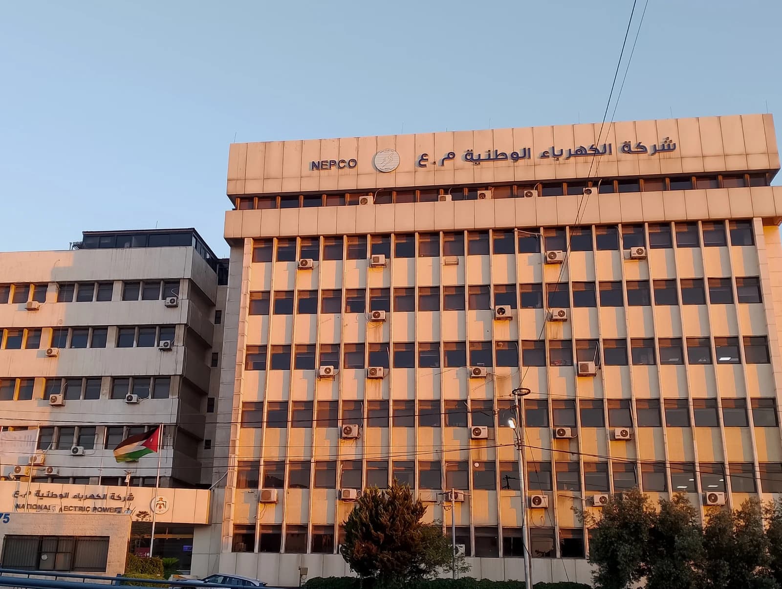 Jordan Electric Power Company building with Arabic and English signage under a clear sky.