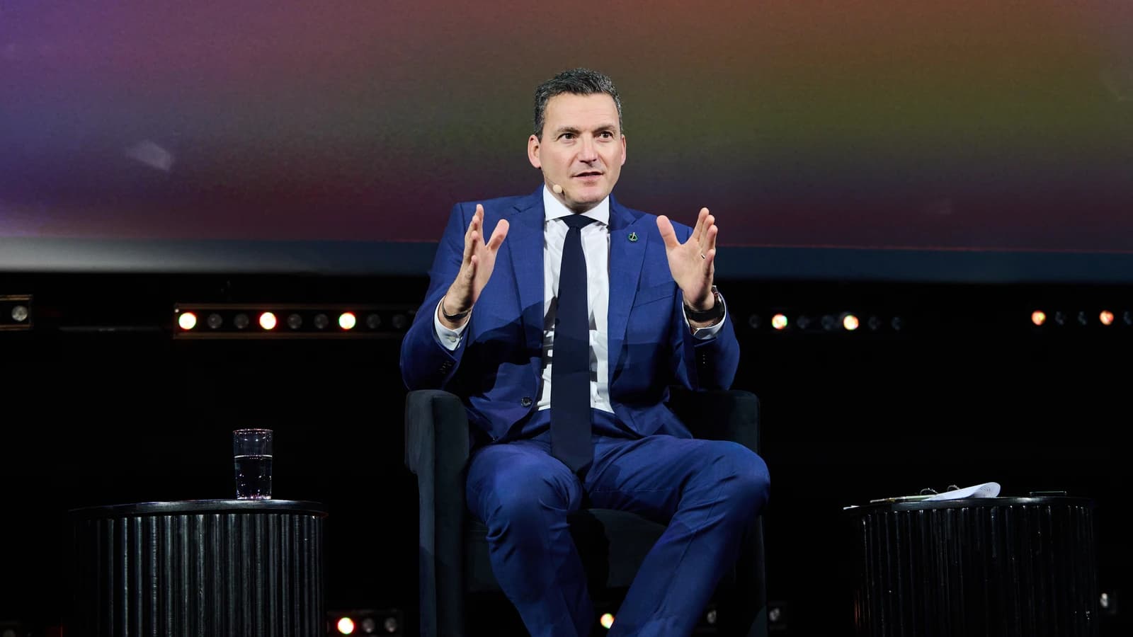 Evan Solomon speaking on a stage during an event, gesturing with his hands.