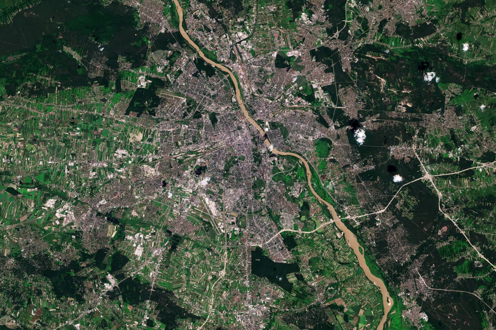Satellite image showing the urban landscape of Warsaw, Poland, bisected by a river.