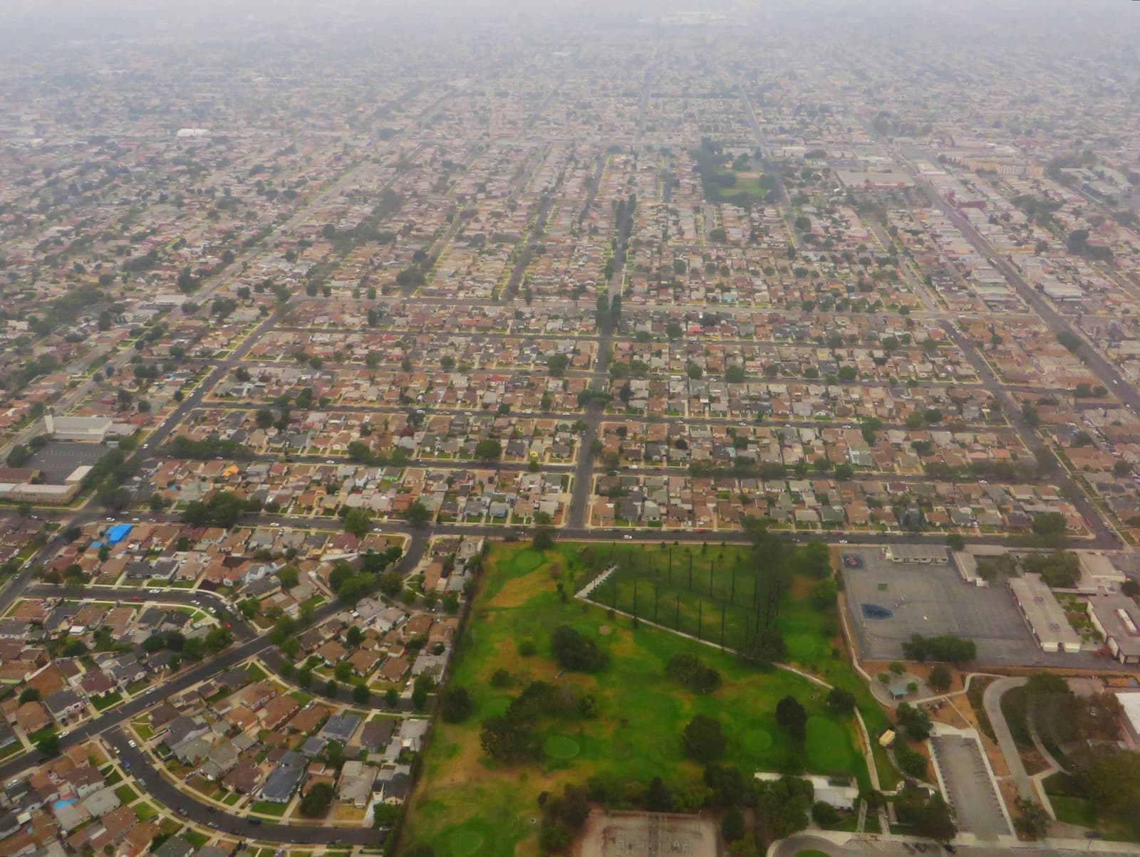 Aerial view of a densely populated residential area with a green park and golf course.