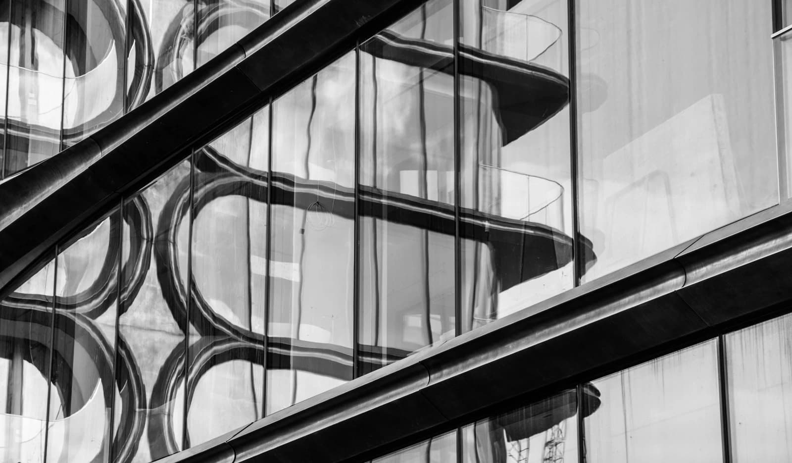 Close-up of modern building facade with reflections on glass panels.