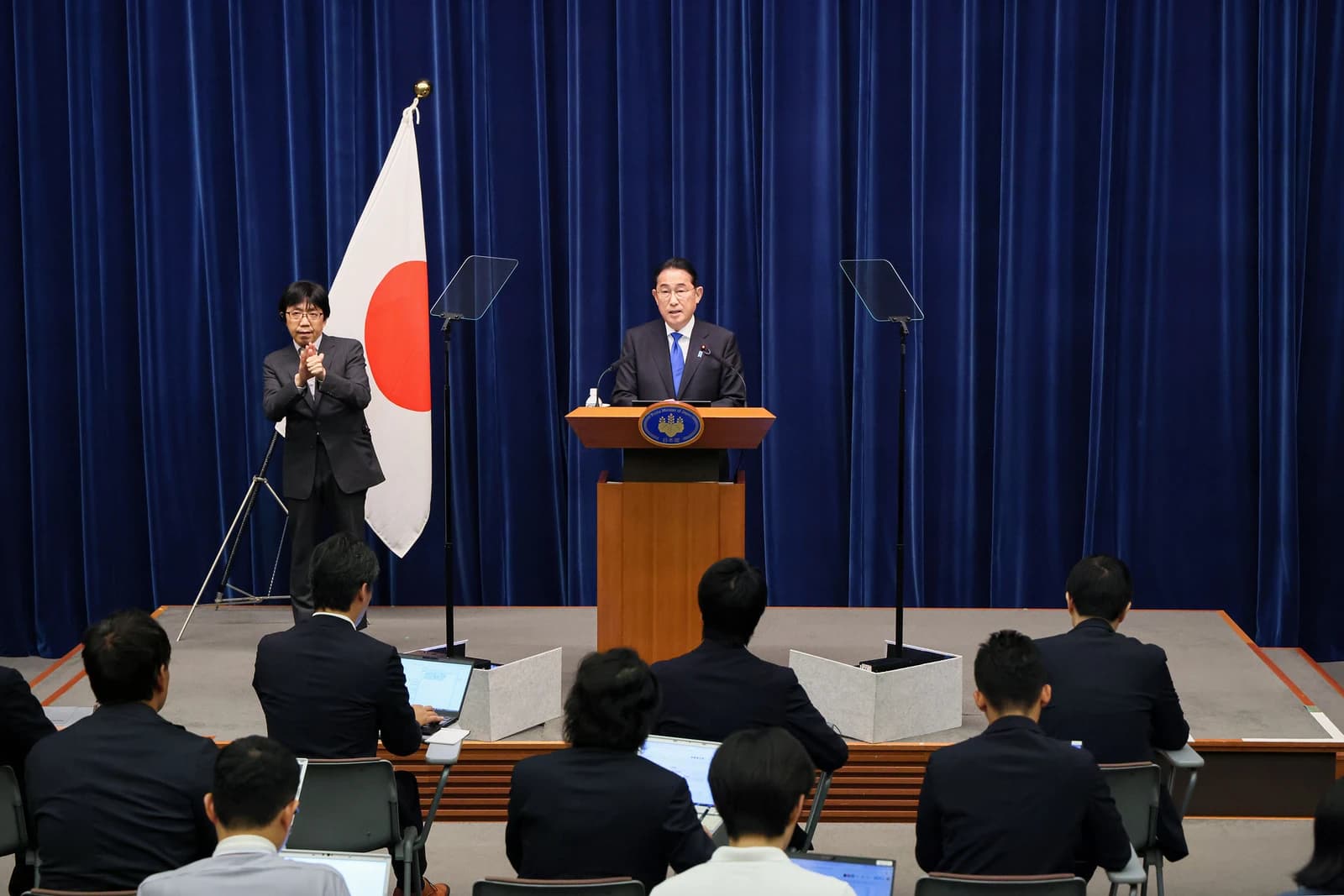 Fumio Kishida, Prime Minister of Japan, speaking at a press conference with an official present.