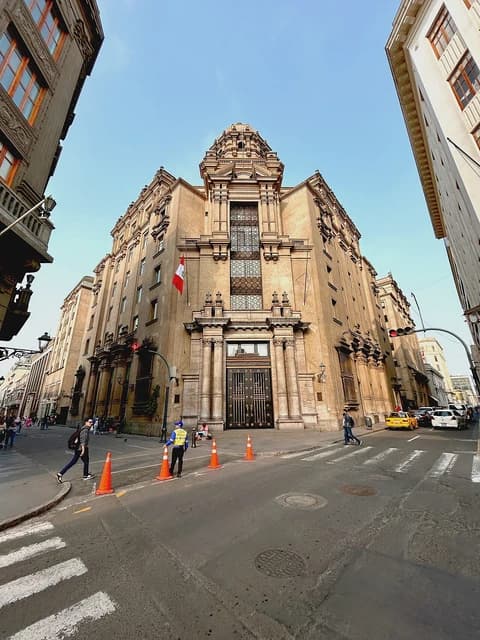 Pedestrians cross the street in front of a grand building in Lima, Peru.