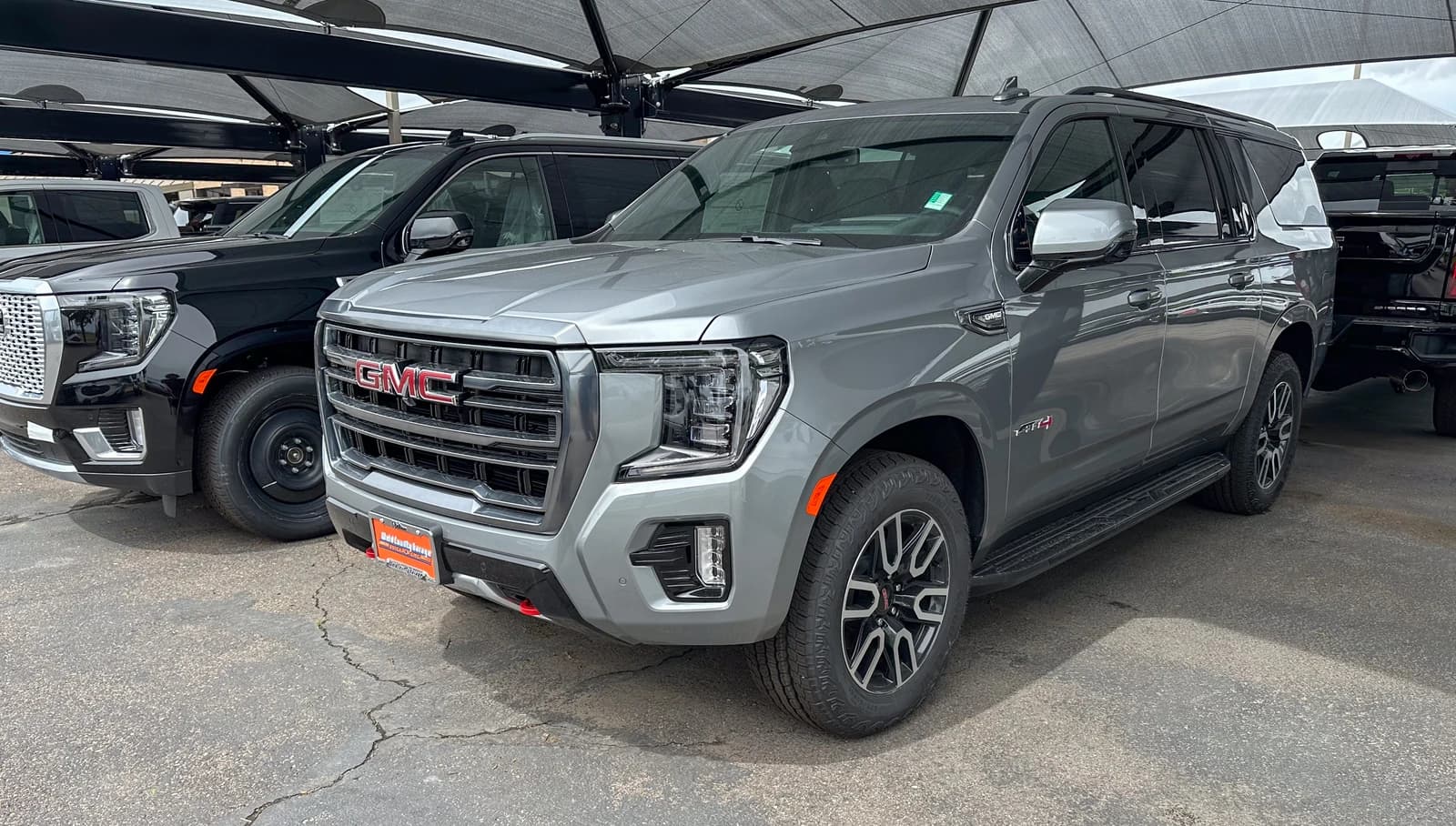 Gray GMC Yukon AT4 SUV parked at a car dealership.