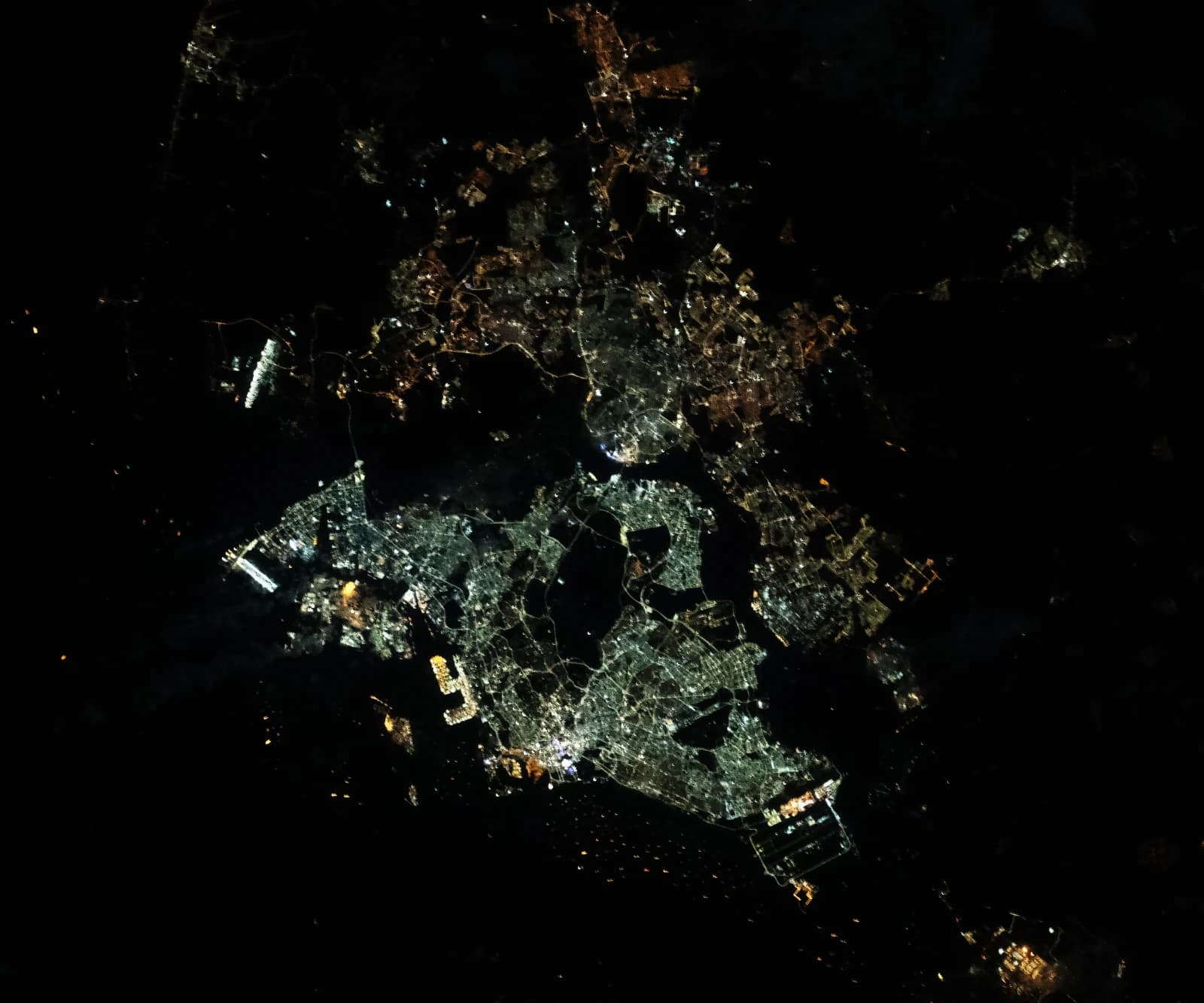 Satellite image showing the illuminated urban areas of Singapore and parts of Malaysia at night.