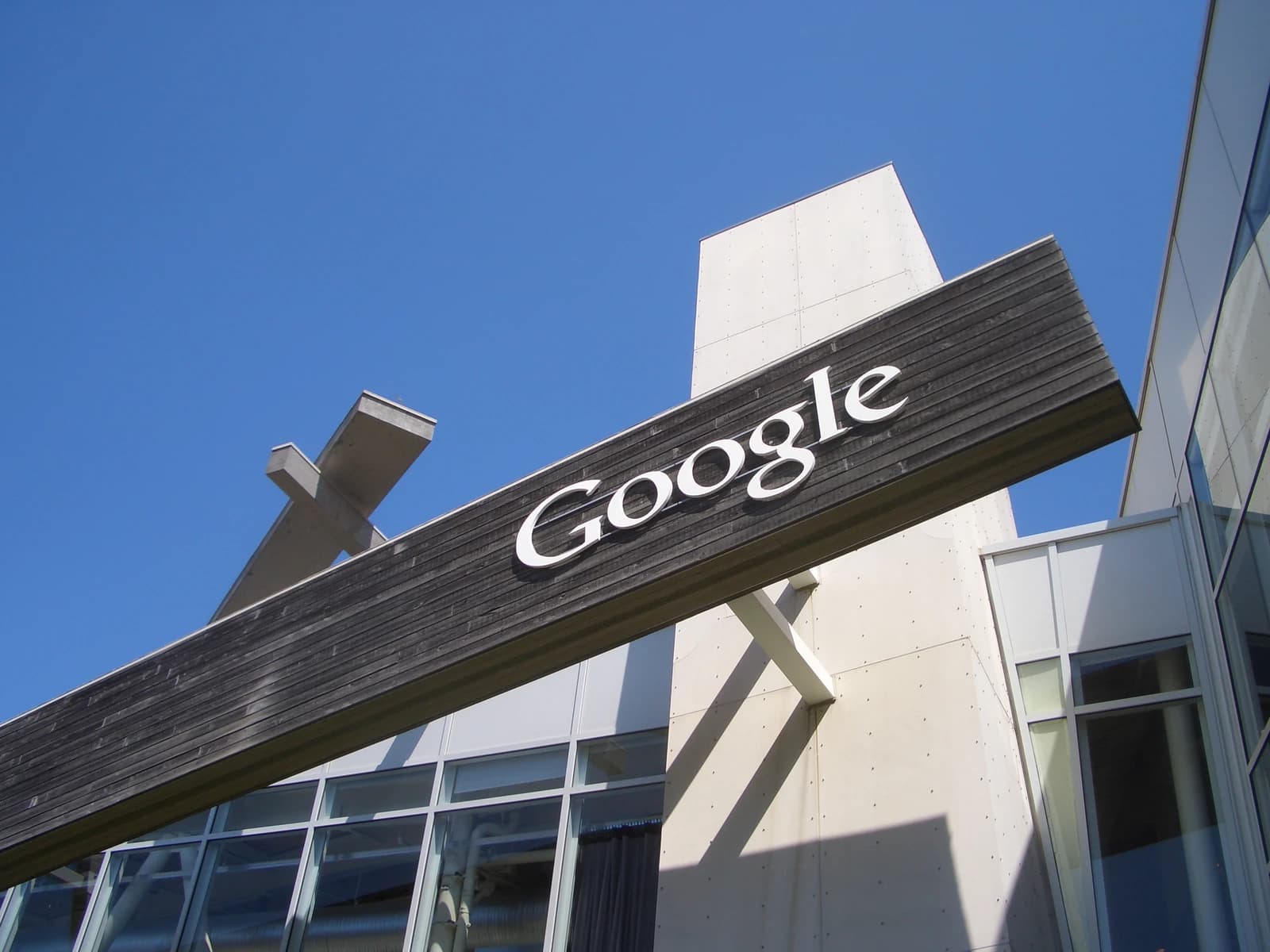 Google sign on the side of a building, clear blue sky background.