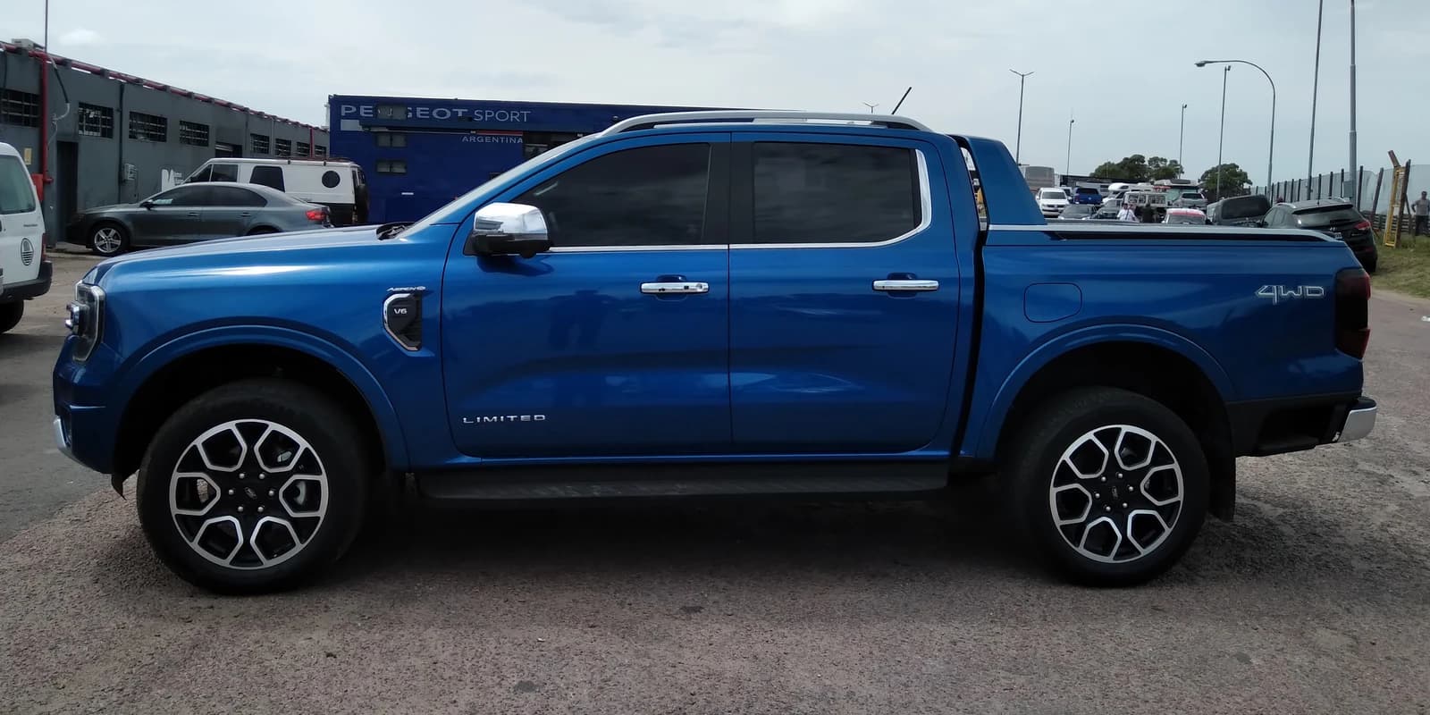 Blue 2024 Ford Ranger V6 Limited pickup truck parked on pavement, side view.