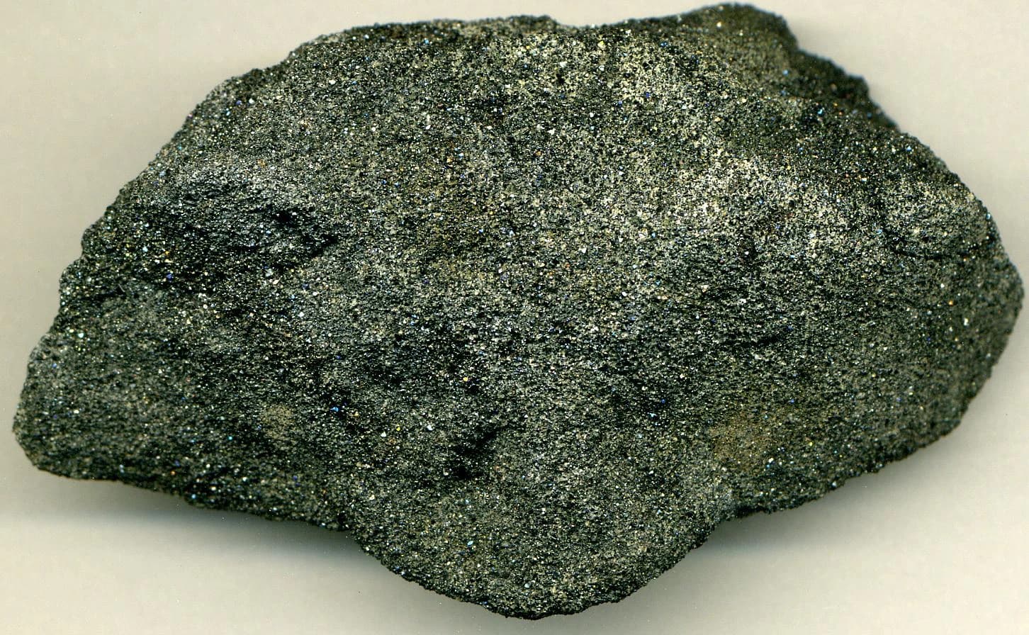 Chromitite mineral sample, a dark gray rock with sparkling flecks.