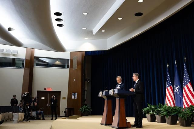 Secretary Antony Blinken speaking at a podium next to NATO Secretary General Jens Stoltenberg.