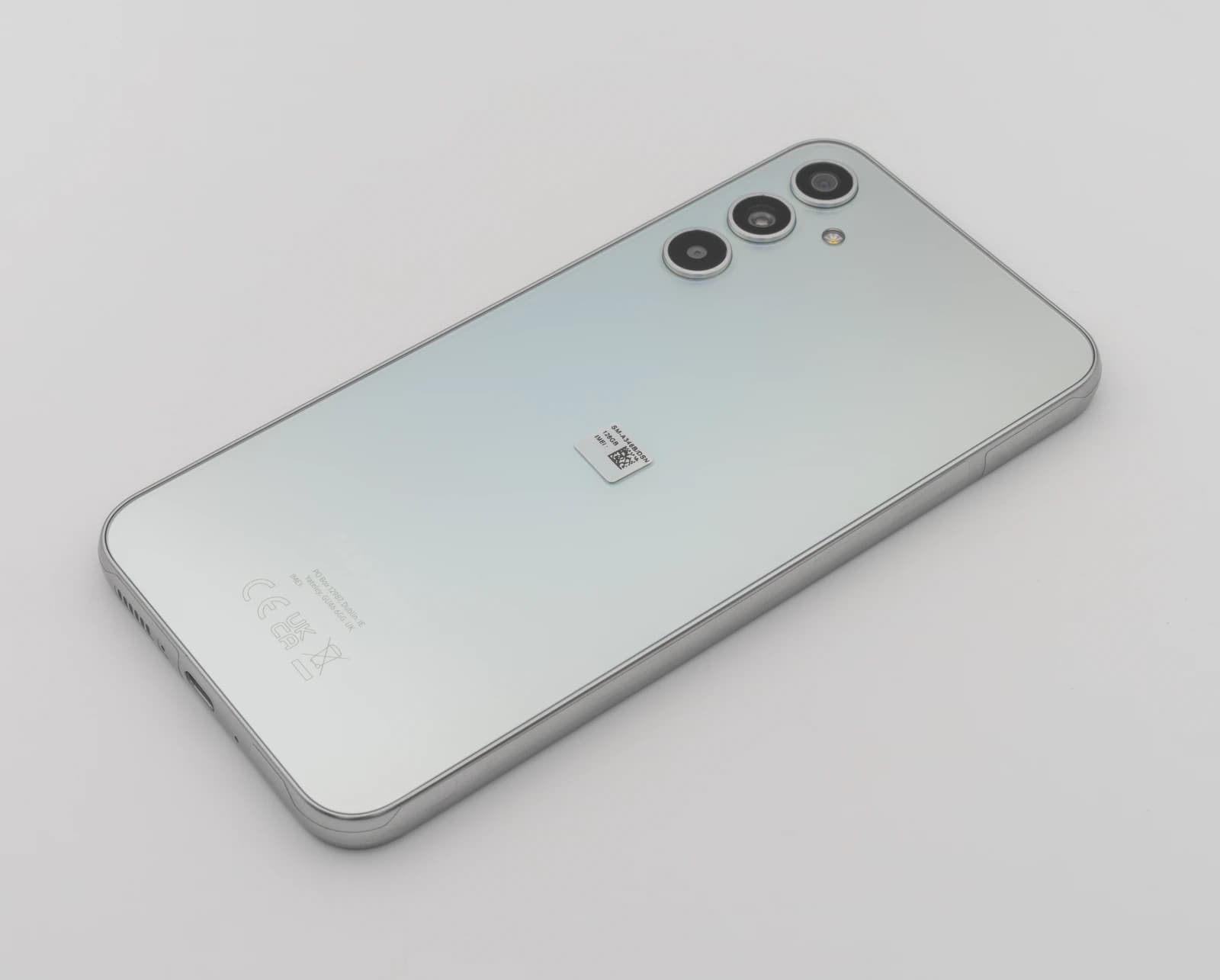 Back of a light gray Samsung Galaxy A34 5G smartphone showing its triple camera array.