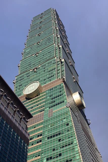 Taipei 101 skyscraper reaching into a blue sky, viewed from a low angle.