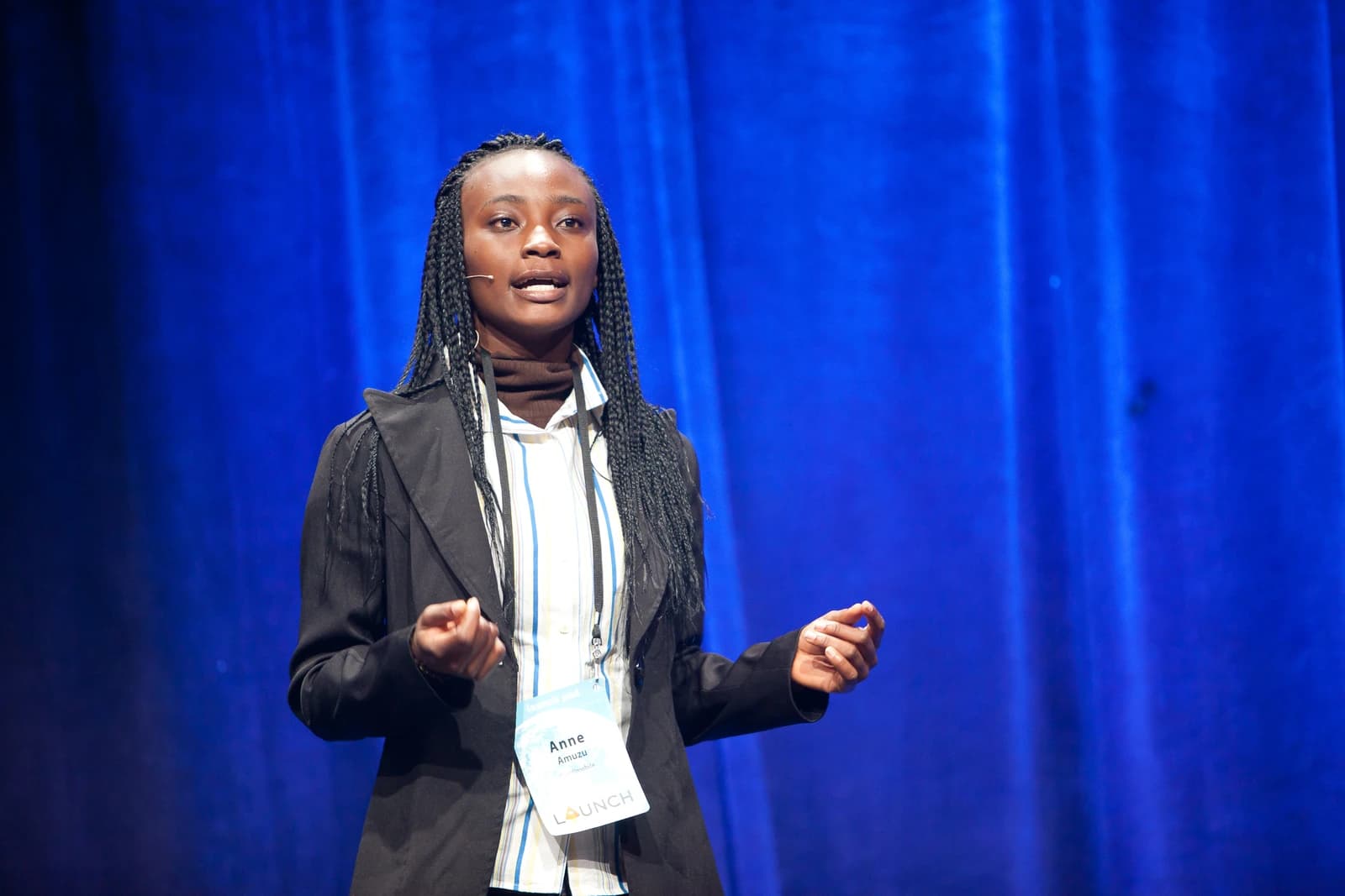 Anne Amuzu speaking at a conference with a blue background.