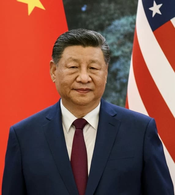 President Xi Jinping standing in front of the Chinese and American flags.