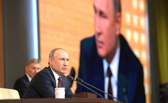Vladimir Putin, President of Russia, speaking at a press conference with microphones in front of him.