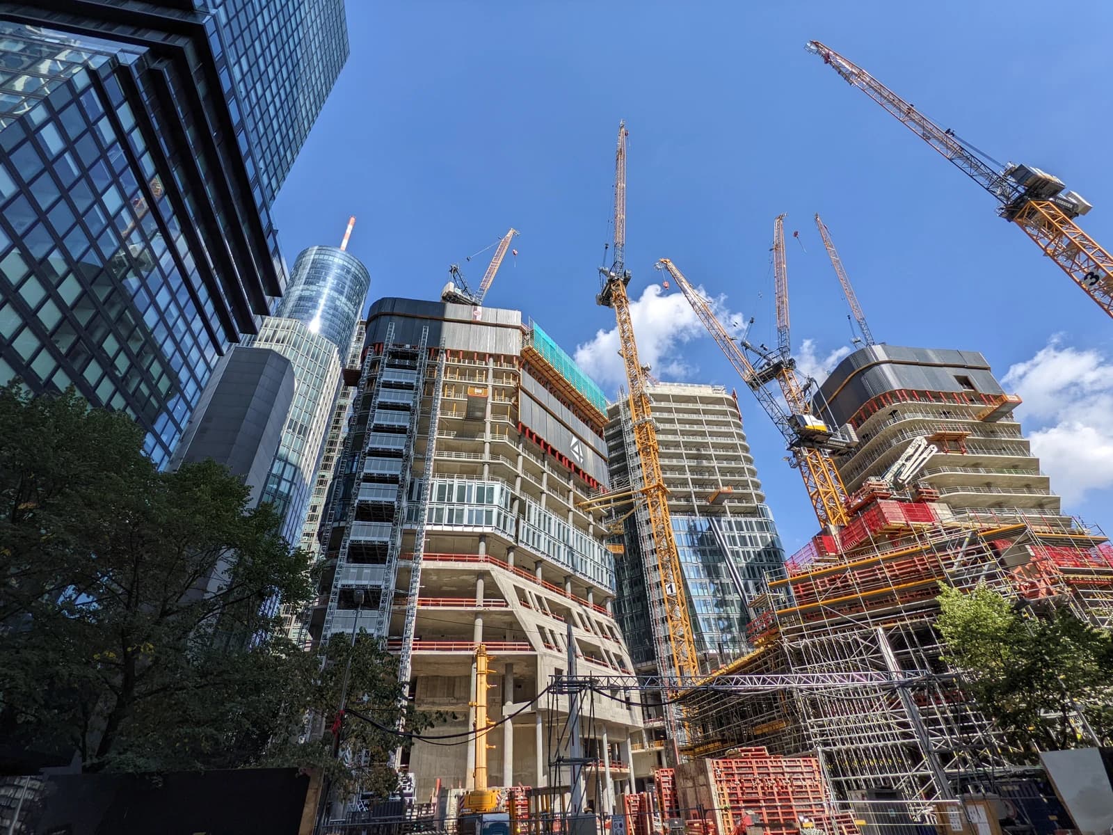 Skyscrapers under construction in Frankfurt, Germany, with multiple cranes against a blue sky.
