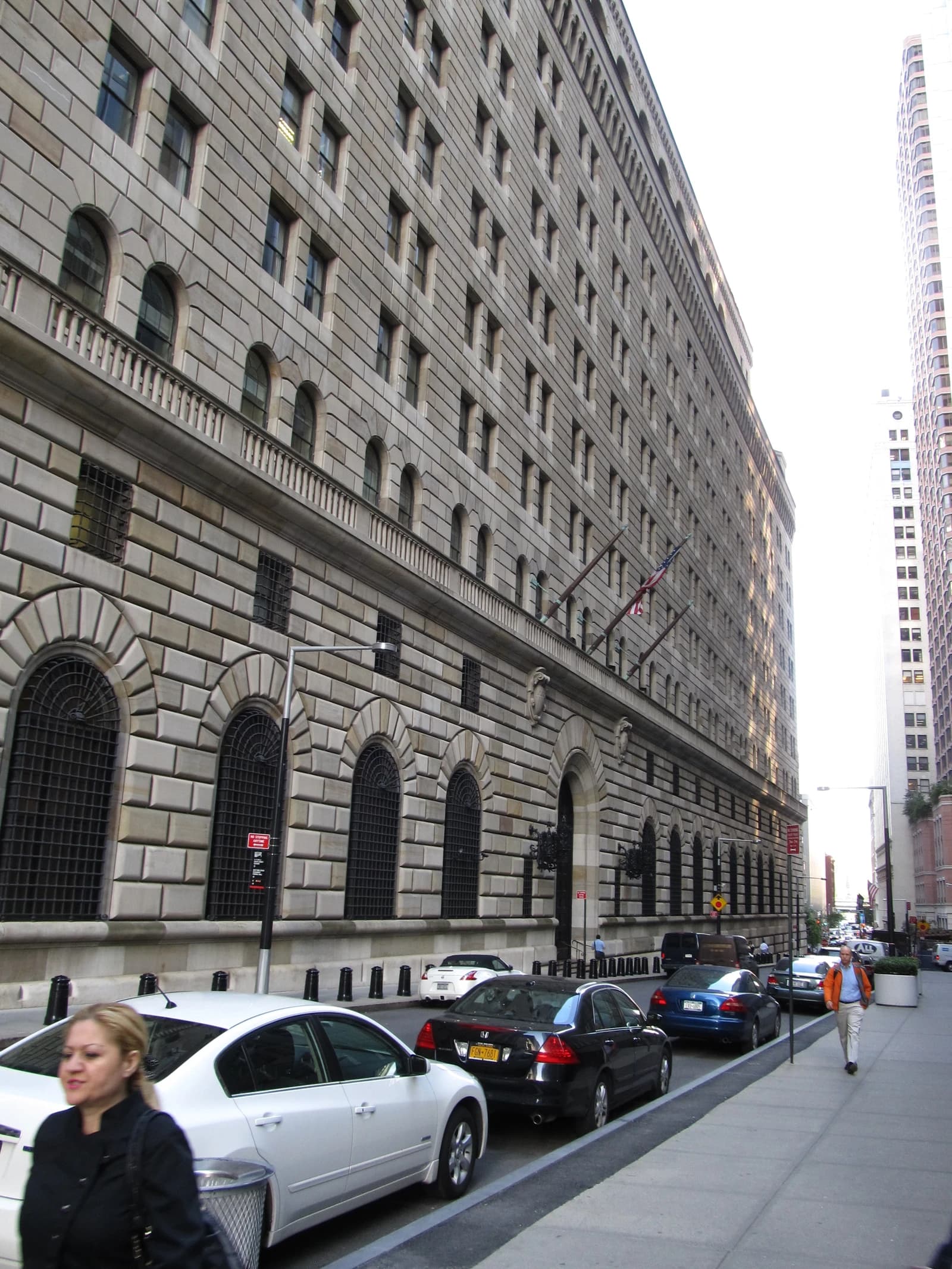 Federal Reserve Bank of New York building in Manhattan, with cars parked along the street.