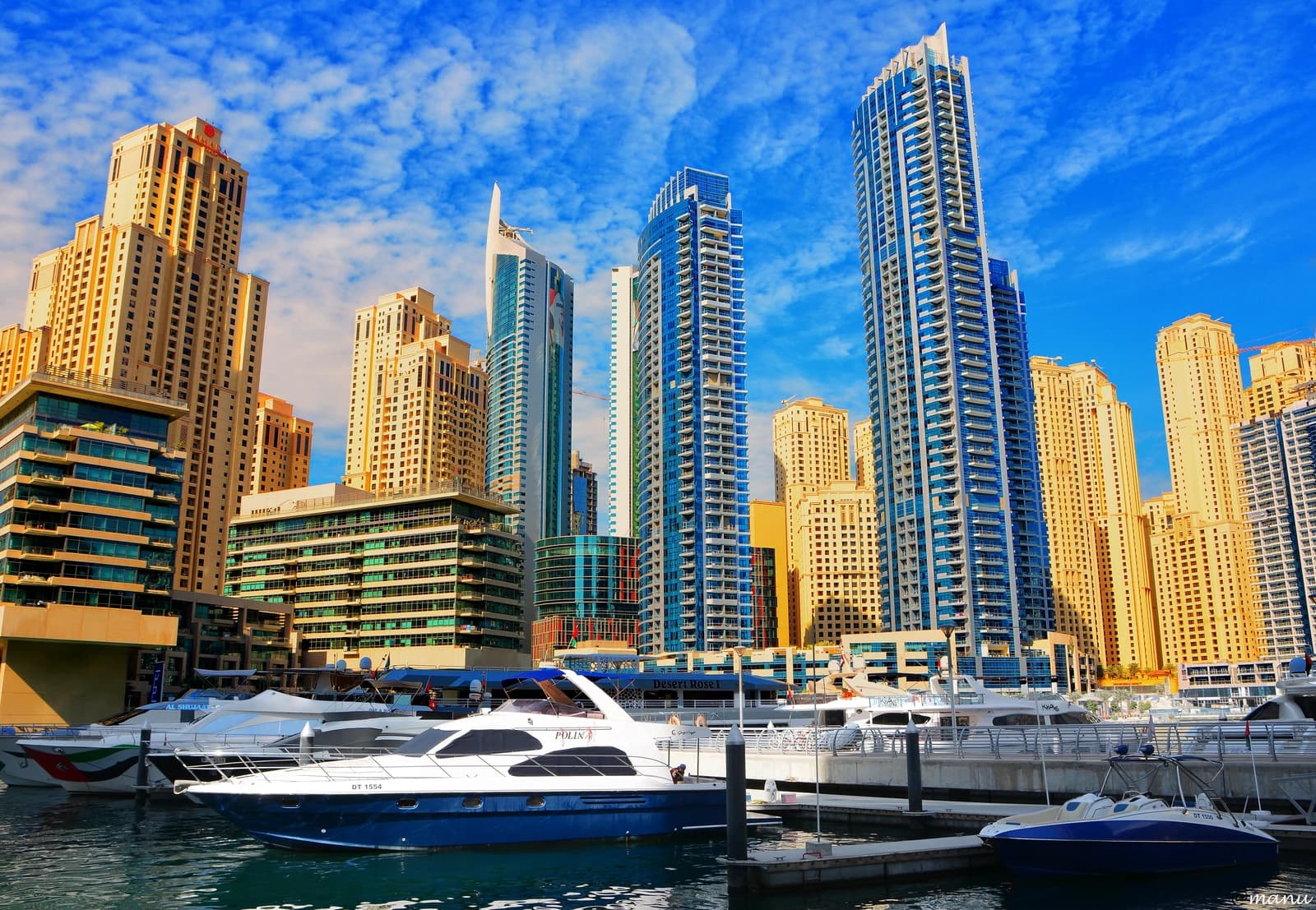 Dubai Marina with multiple tall residential buildings and luxury yachts docked in the water.