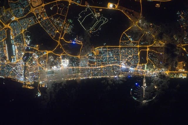 Dubai city lights and Palm Jumeirah at night from an aerial perspective.