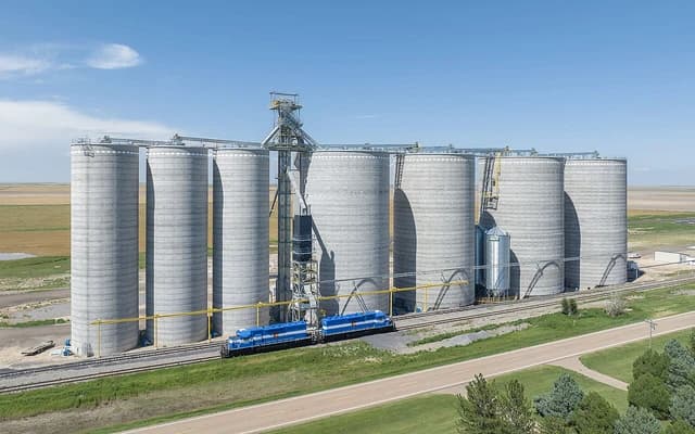 Grain elevator facility in Colorado, with numerous large silos and a train on tracks.