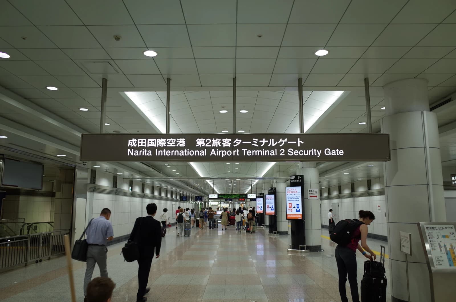 Travelers walk through Narita International Airport Terminal 2 security gate.