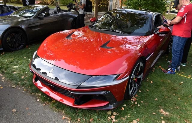 Red Ferrari 12Cilindri sports car, front quarter view, parked outdoors on grass.