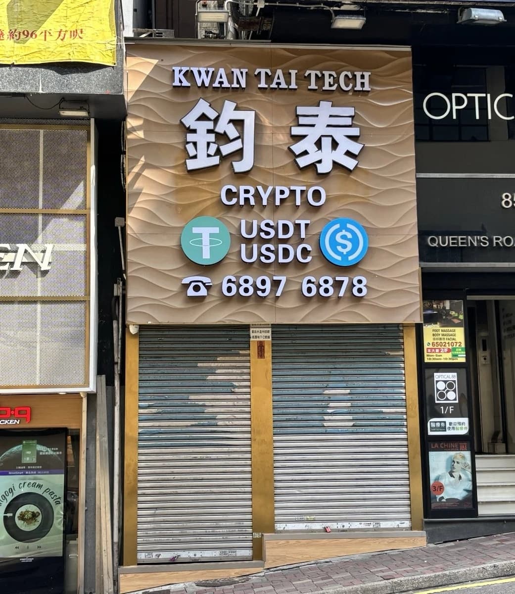 Storefront sign for Kwan Tai Tech featuring 'CRYPTO USDT USDC' text and phone number.