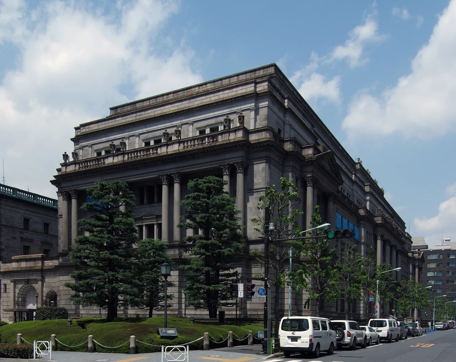 Bank of Japan headquarters building exterior with classical architecture and parked vehicles.