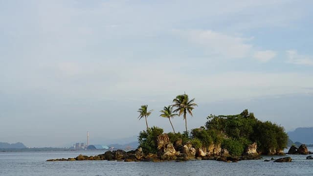 Labuhan Angin coal-fired power plant and an island with palm trees.