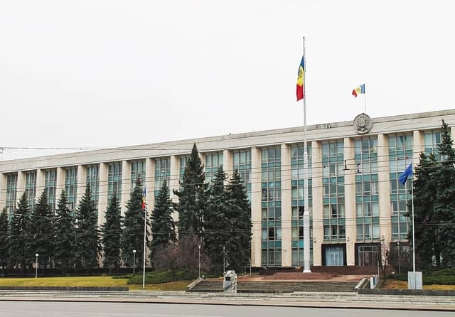 Exterior of a large, multi-story building with many windows and flags flying out front.