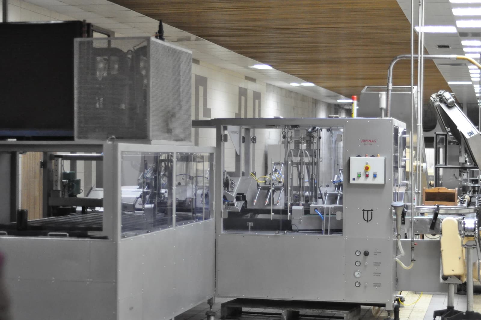 Industrial machinery inside a production facility with various pipes and control panels.