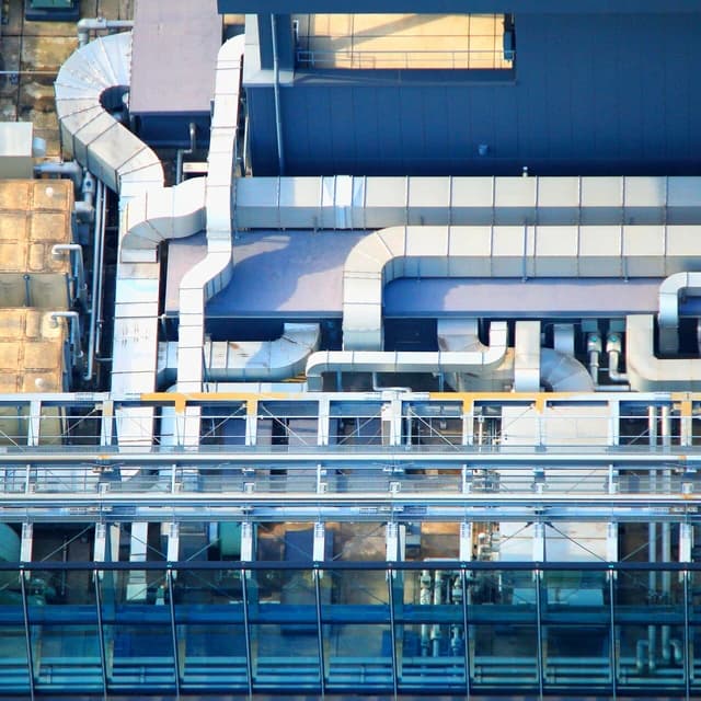 Air conditioning units and ductwork on a large building's roof in Tokyo.