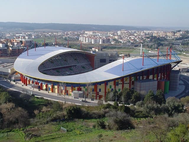 Aerial view of Estádio de Leiria with surrounding city buildings under a clear sky.