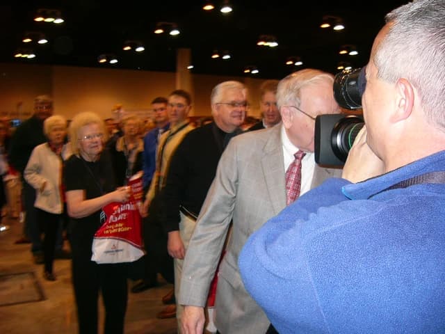 Warren Buffett being photographed by an attendee at an event.