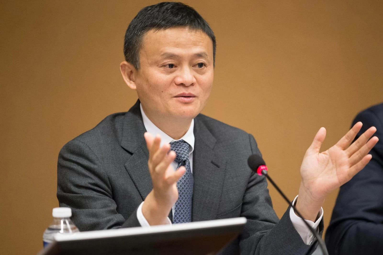 Jack Ma, co-founder of Alibaba Group, speaking at a podium with microphone.