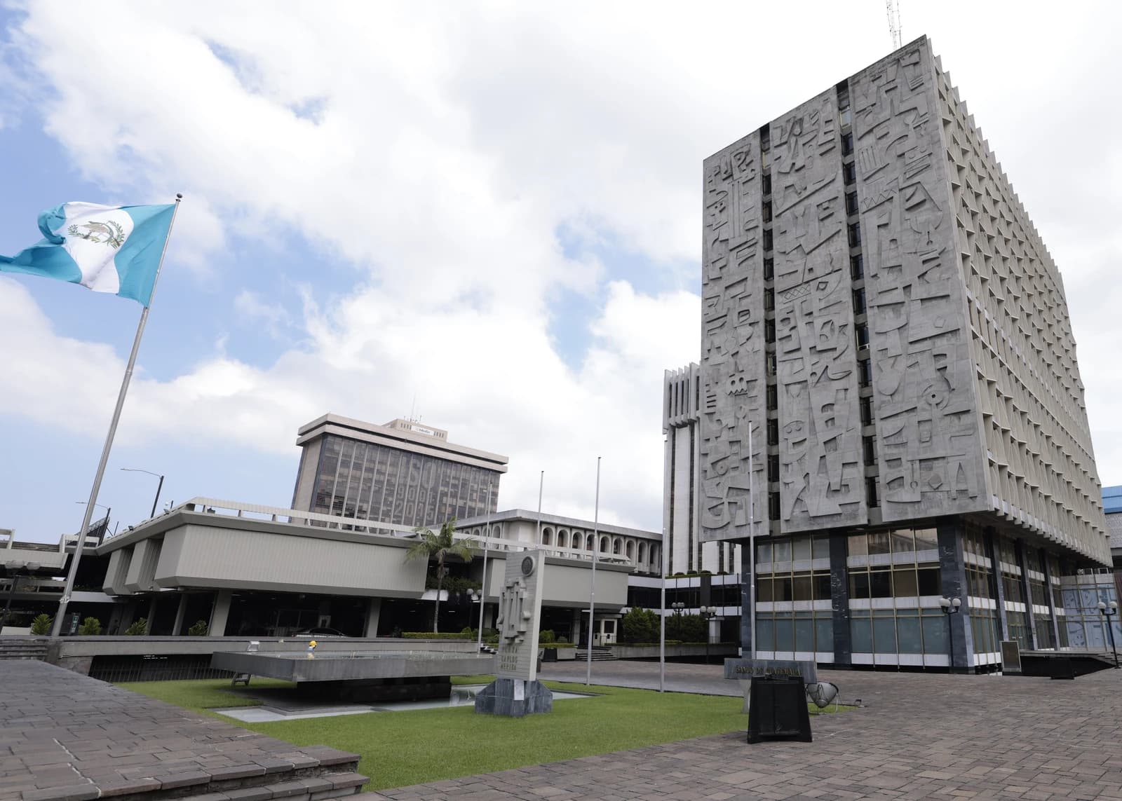 Exterior view of the Bank of Guatemala building under a cloudy sky.