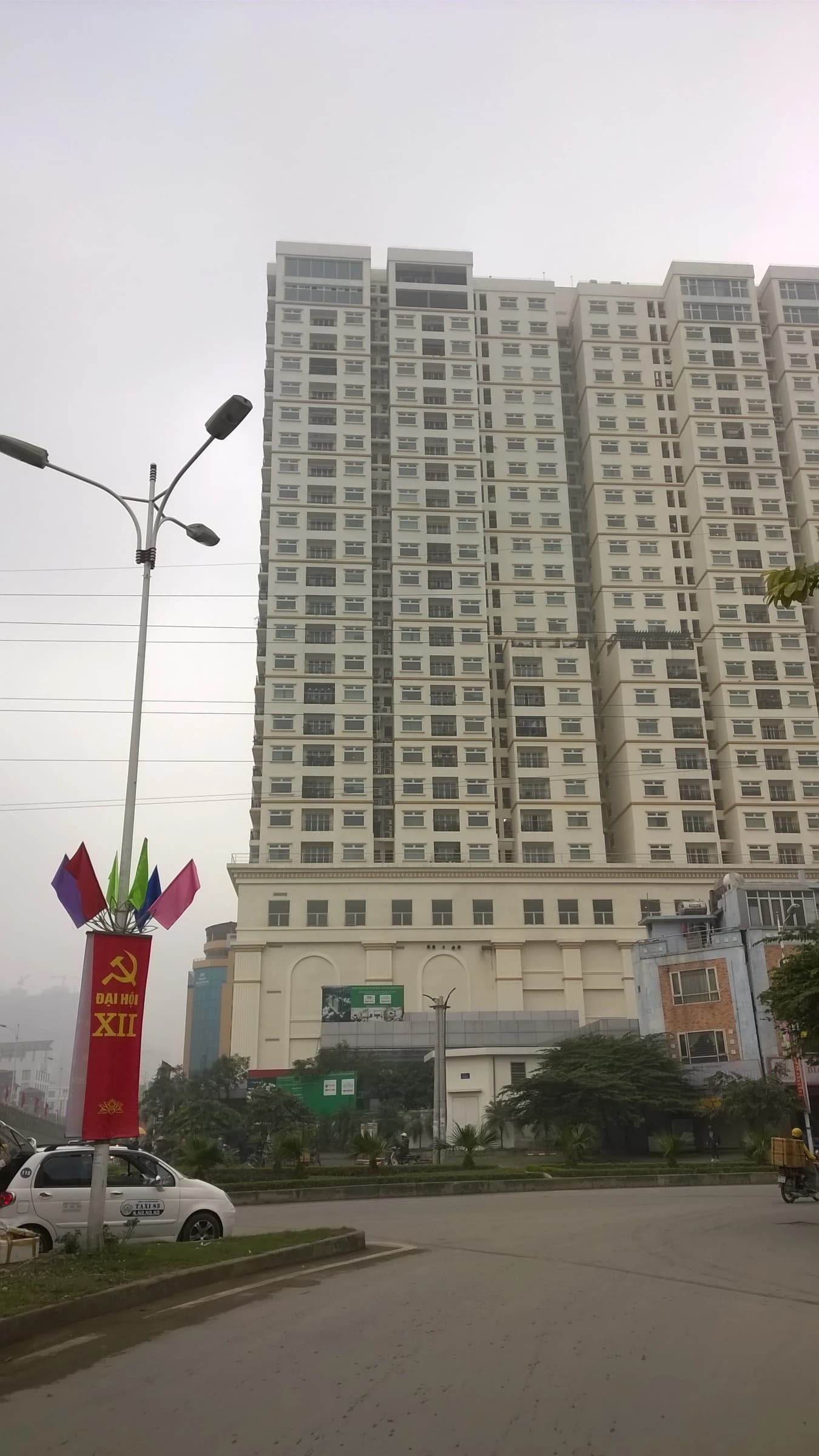 Tall apartment buildings on Minh Khai street in Hanoi, Vietnam under a hazy sky.